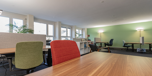 Spacious and well-lit Kreuzstrasse 24 office space rental in Zürich Seefeld with colorful chairs and modern desks.