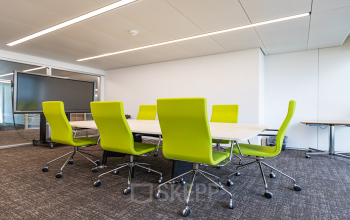A brightly lit conference room with green chairs and modern amenities at Dufourstrasse 43 office space rental in Zürich Seefeld.