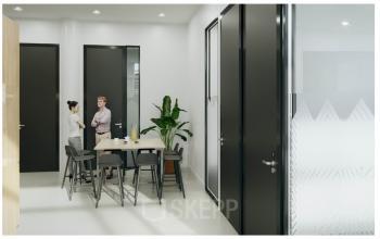 Modern Zurich Seefeld office space rental at Dufourstrasse 49 with two professionals engaged in a discussion around a meeting table, natural light illuminating the area.