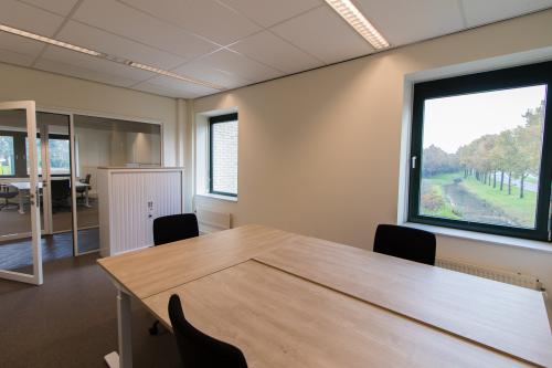 Modern office space rental at Hanzelaan 351-361, Zwolle Centraal Station, featuring a well-lit room with desks and chairs overlooking a green area.