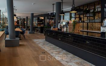 Modern, furnished office space for rent at Assendorperdijk 1, Zwolle features stylish interiors with a spacious counter area and community seating, ideal for collaborative work.