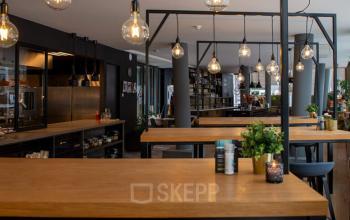 Modern office space rental in Zwolle with wooden tables and stylish lighting, offering a practical environment for business activities at Assendorperdijk 1.