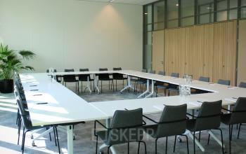 Modern conference room with U-shaped table arrangement and chairs at Zwartewaterallee 56, Zwolle. Ideal office space rental for meetings.