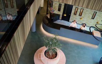 Reception area of office at Zwartewaterallee 56, Zwolle, with a curved desk, two people working at computers, modern design, and a central plant feature.