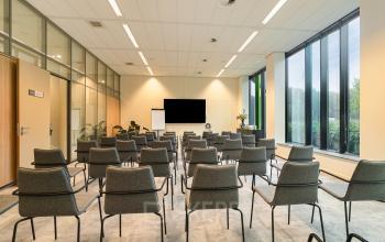 Modern conference room with rows of grey chairs and a large screen at Zwartewaterallee 56, ideal for office space rental.