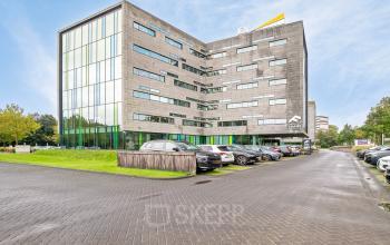 Exterior view of Zwartewaterallee 56 in Zwolle, featuring a modern office building with ample parking space. Ideal for office space rental.