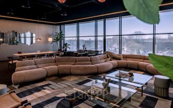 Stylish, furnished office space with large windows, curved sofa, and modern decor, ideal for office space rental in Zwolle.