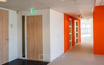 Bright hallway at Dokter van Deenweg 1 in Zwolle, showcasing vibrant orange walls and multiple doorways, ideal for office space rental.