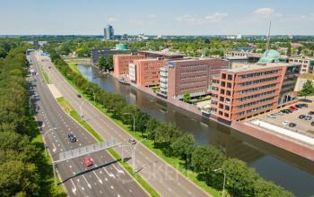 Aerial view of office buildings along a canal at Zuiderzeelaan 15-25, Zwolle, featuring modern architecture. Ideal for office to rent opportunities, surrounded by greenery and accessible roads.