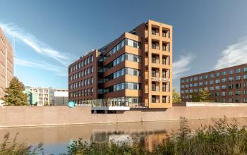 View of a modern office building located at Zuiderzeelaan 15-25, Zwolle, featuring glass windows and near a canal, ideal for office space rental.