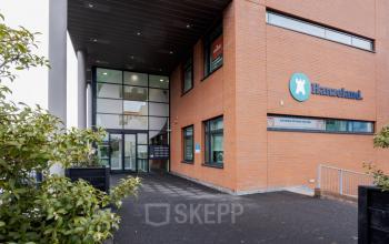 Entrance of office building at Zuiderzeelaan 15-25 in Zwolle, featuring glass facade and brick exterior, perfect for office space rental opportunities.
