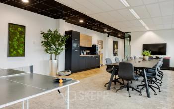 Modern office space with large tables and ergonomic chairs, featuring a kitchen area and a ping pong table. Ideal for office space rental in Zwolle at Zuiderzeelaan 15-25.