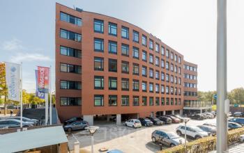 Exterior view of a modern office building at Zuiderzeelaan 15-25, Zwolle. The brick façade and large windows complement the surrounding parking area and reflect the bustling potential of office space rental.