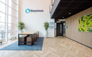 Modern entrance area at Zuiderzeelaan 15-25, Zwolle featuring a sleek table and chairs, enhanced by plant decor. Ideal for businesses looking for office space rental.