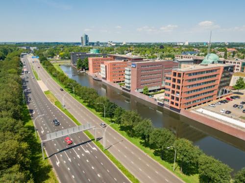 Aerial view of office buildings along a canal at Zuiderzeelaan 15-25, Zwolle, featuring modern architecture. Ideal for office to rent opportunities, surrounded by greenery and accessible roads.