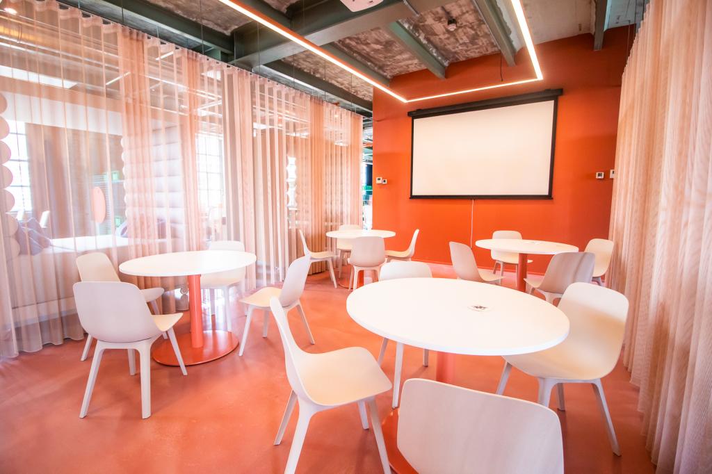 In diesem Bürodesign wird die Farbe Orange mit weißen Accessoires und Möbeln kom